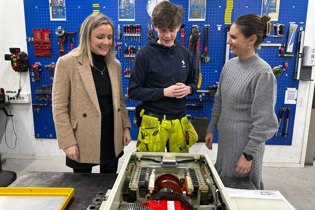 Sporveiens signalmontørlærling, Herman Osvold Askheim forklarer  byråd for miljø og samferdsel Marit Vea (V) og byråd for utdanning Julie Remen Midtgarden (H) om signalsystemet og demonstrerte hvordan en drivmaskin fungerer mekanisk.