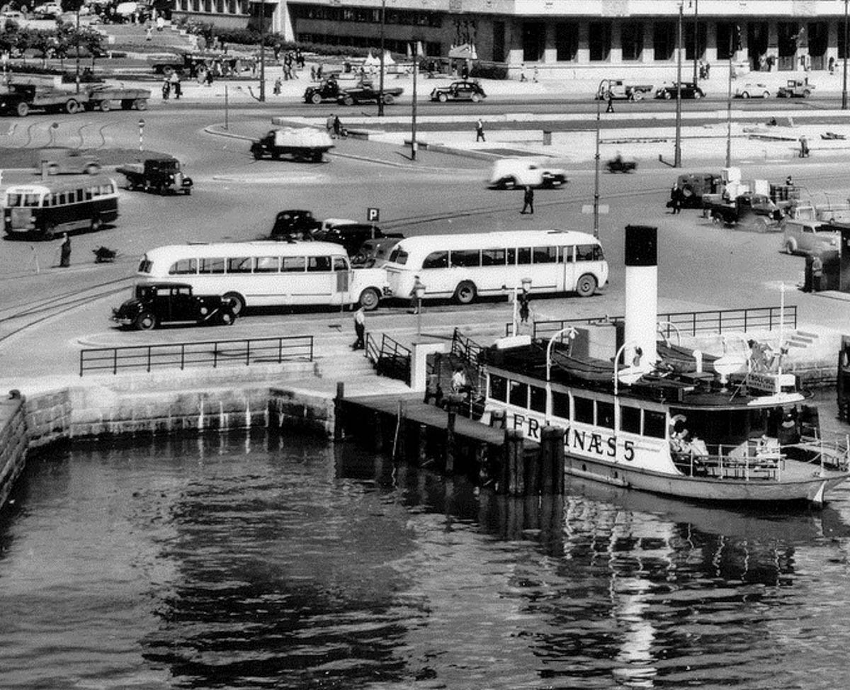 Rådhusplasser med biler, busser og båter.